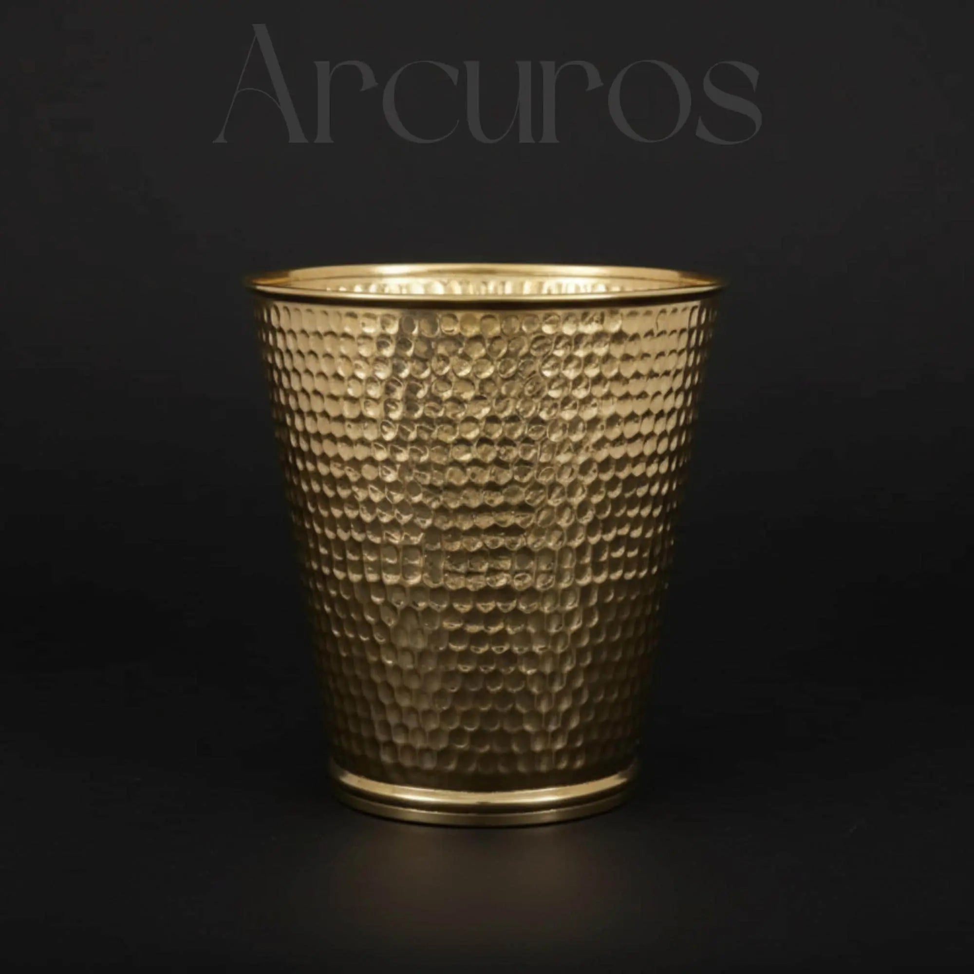 A handcrafted, unlacquered brass waste bin with Moroccan engravings, sitting on a tiled bathroom floor.
